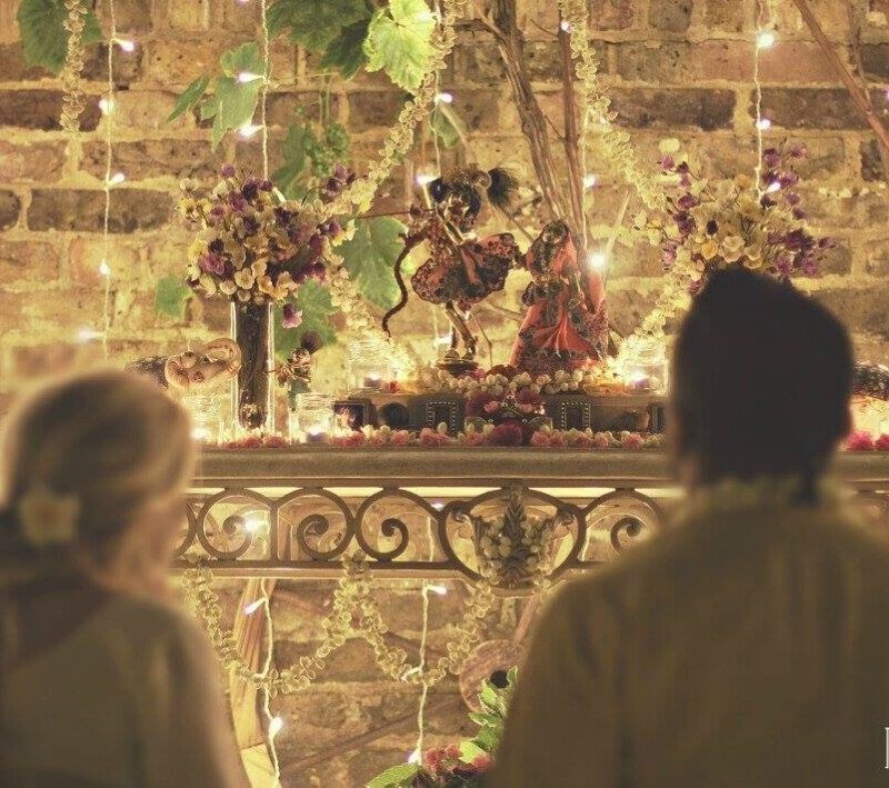 A man and a woman look upon the icon forms of Radha and Krishna.