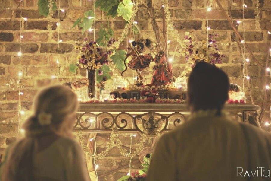 A man and a woman look upon the icon forms of Radha and Krishna.