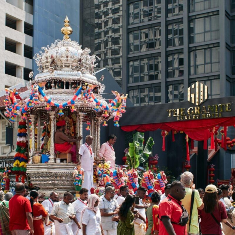 A bustling Thaipusam procession winds through the streets of Malaysia, anchored by the ornate silver chariot carrying Murugan, the “icon of war.”
