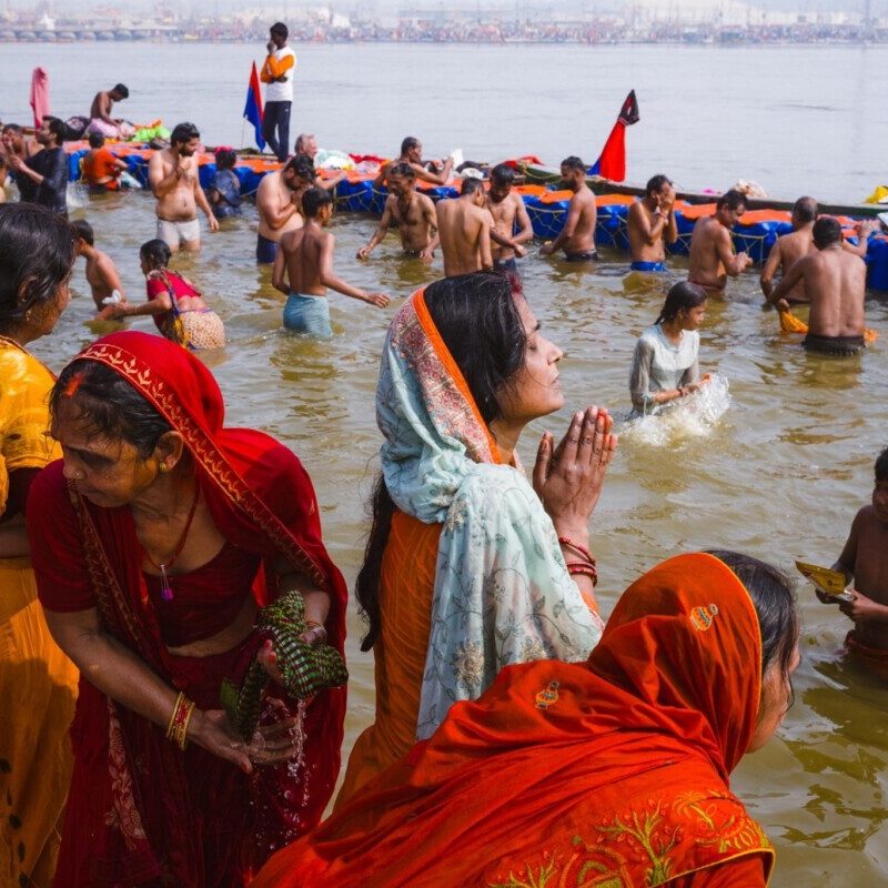 A woman praying while standing in the water at the 2025 Kumbh Mela, Prayagraj, India