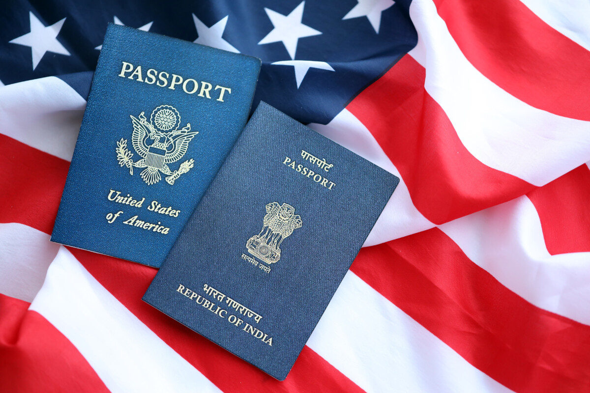 two passports, one of the U.S. and one of India sitting left of center on top of a loosely placed American flag
