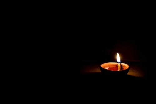 A lighted oil earthen lamp set in darkness.