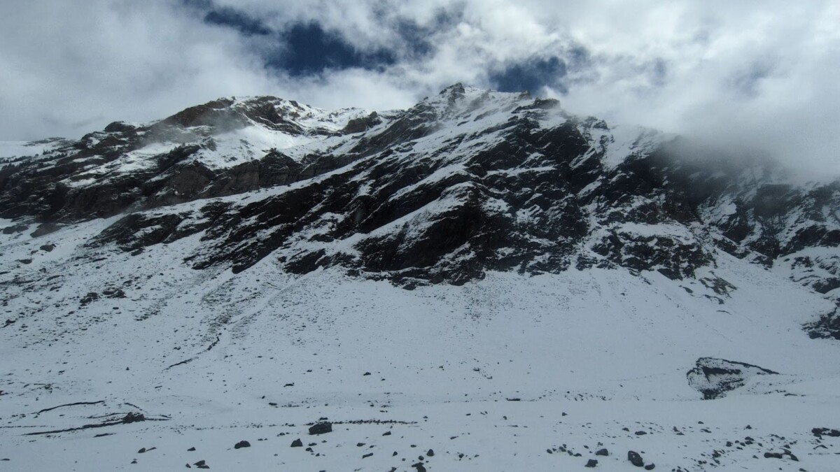 Snow on mountains with the clouds touching the peaks.